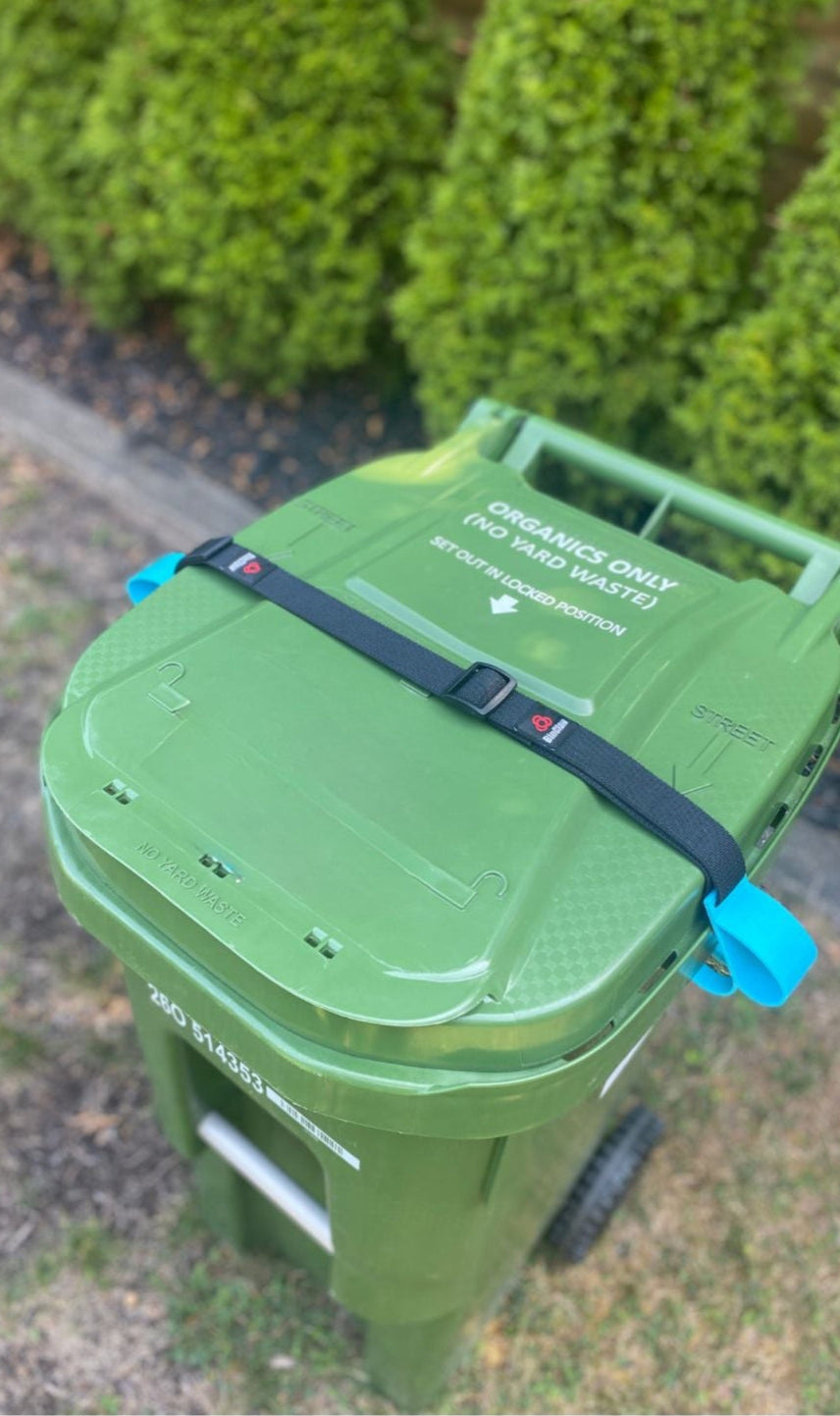 Green recycling bin with a black strap on a grassy background
